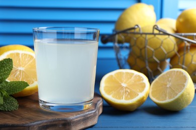 Fresh juice in glass, lemons and mint on blue wooden table, closeup