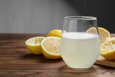 Photo of Fresh juice in glass and lemons on wooden table, closeup. Space for text