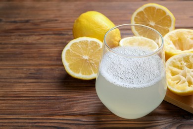 Photo of Fresh juice in glass and lemons on wooden table, closeup. Space for text