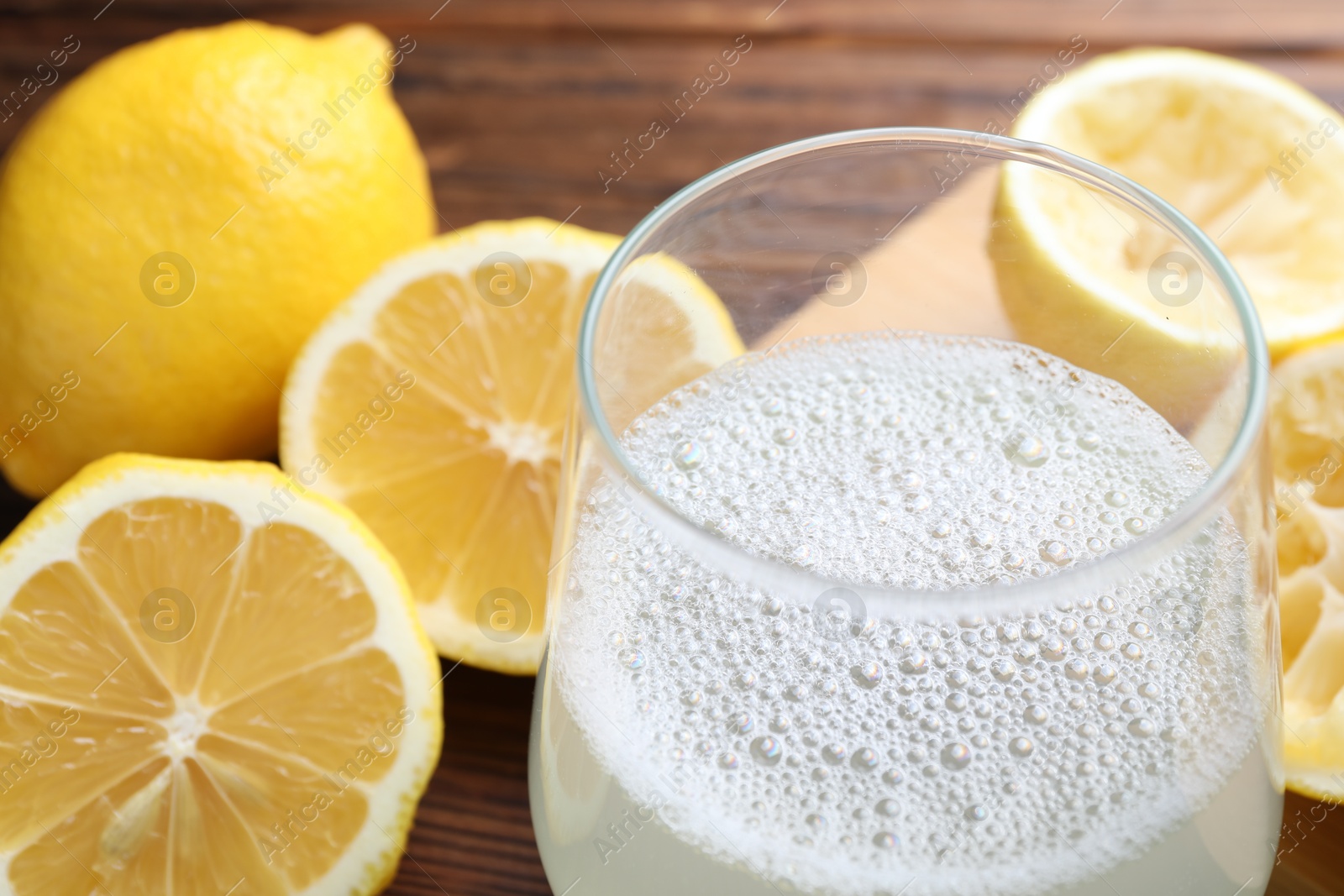 Photo of Fresh juice in glass and lemons on table, closeup