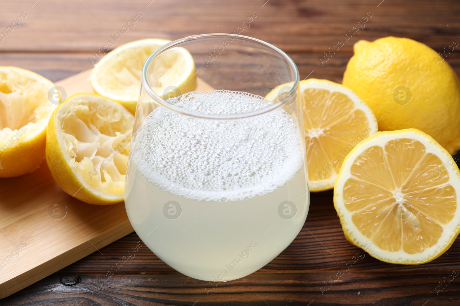 Photo of Fresh juice in glass and lemons on wooden table, closeup