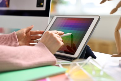 Photo of Designer working with tablet at table in office, closeup