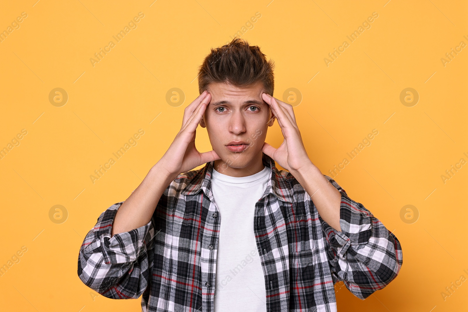 Photo of Young student having stress before exam on yellow background