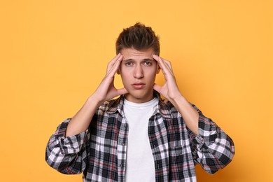 Young student having stress before exam on yellow background