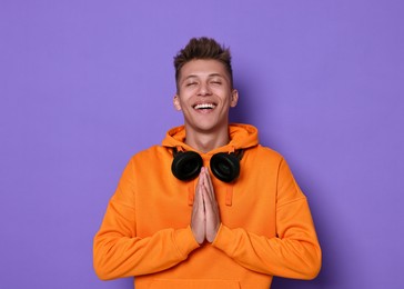 Photo of Young student grateful about his good exam result on violet background