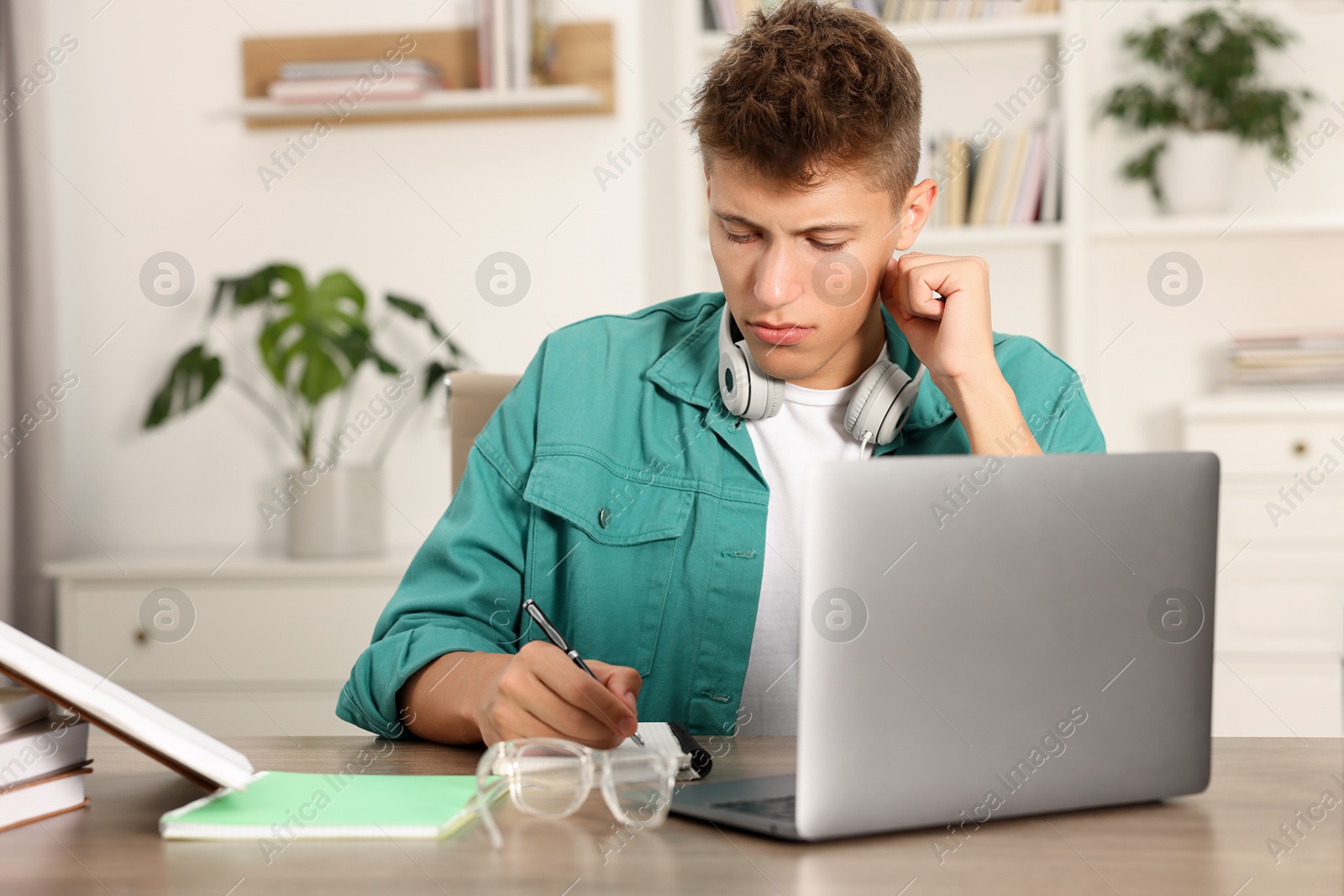 Photo of Student with headphones studying at table indoors