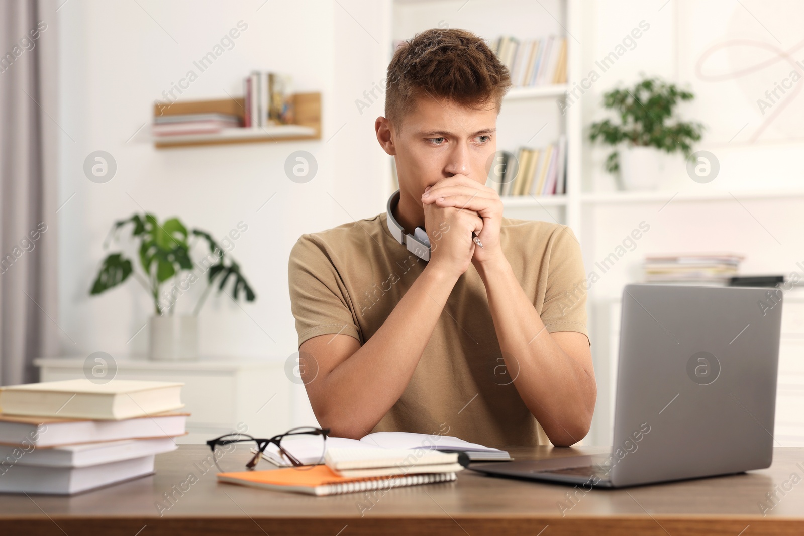 Photo of Student studying with laptop at wooden table indoors