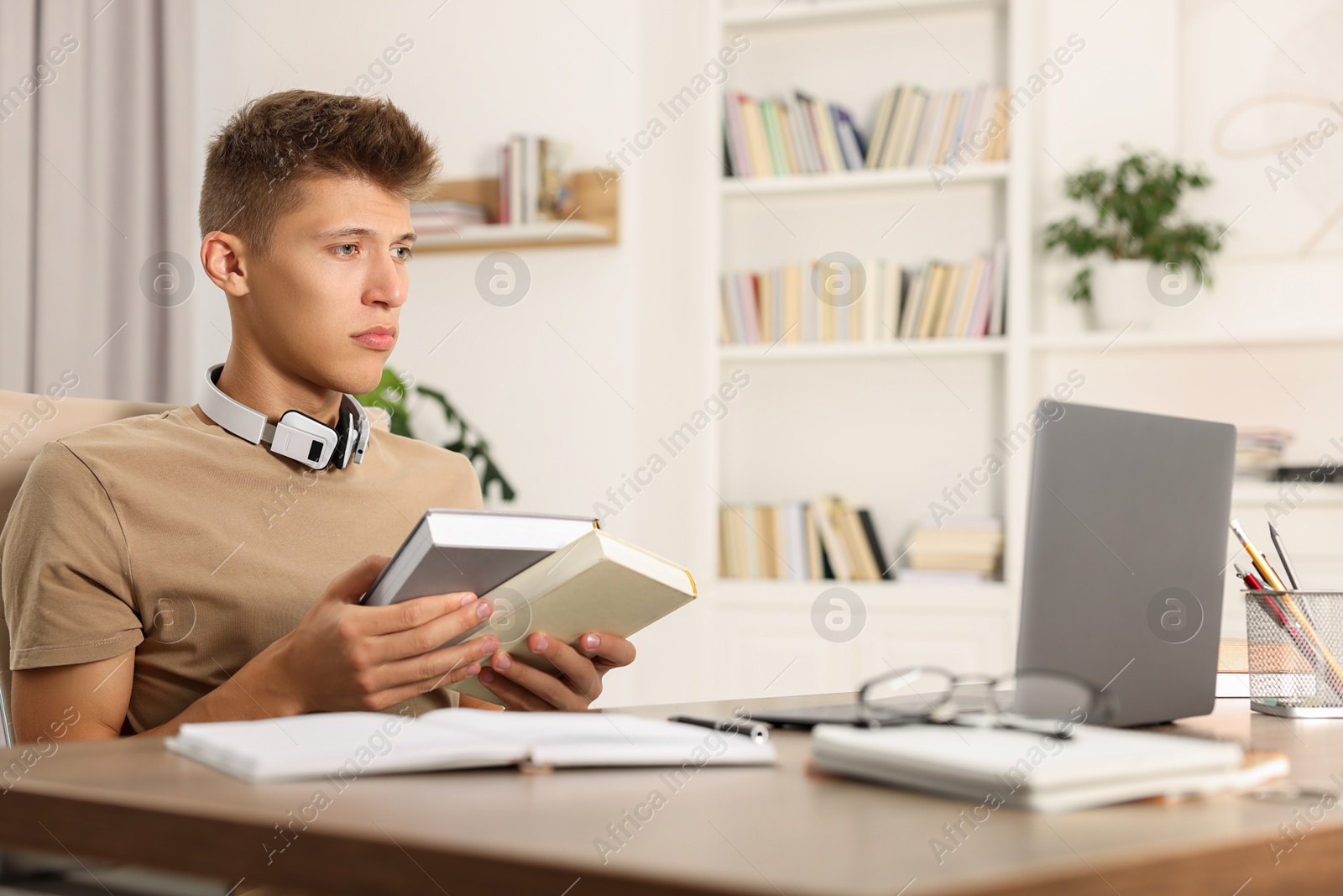 Photo of Student with books studying at table indoors