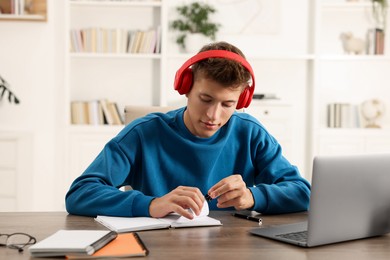 Student in headphones studying at wooden table indoors