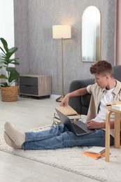 Student studying with laptop on floor at home