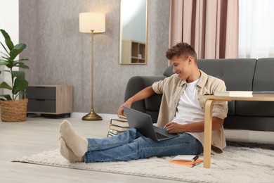 Student studying with laptop on floor at home