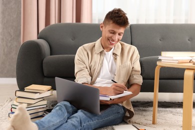 Student taking notes while studying on floor at home