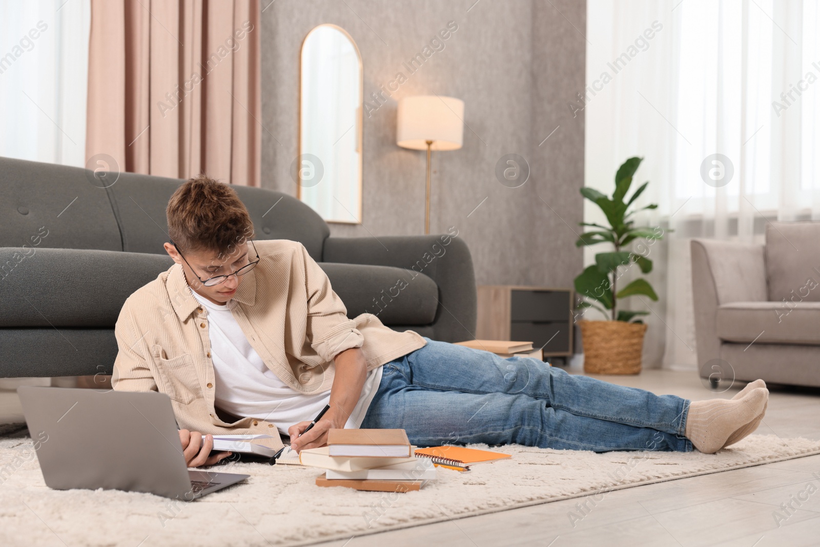 Photo of Student in glasses studying on floor at home