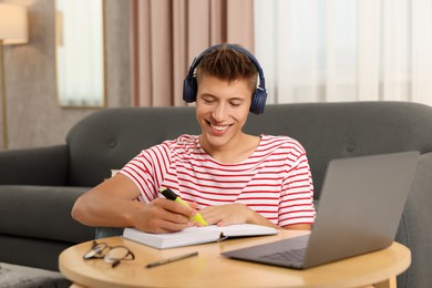 Student in headphones studying at table indoors