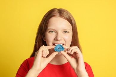 Photo of Teenage girl eating tasty gummy candy on yellow background