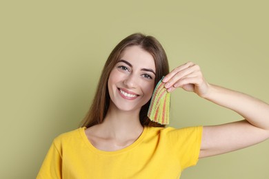 Photo of Happy young woman with tasty rainbow sour belts on olive background