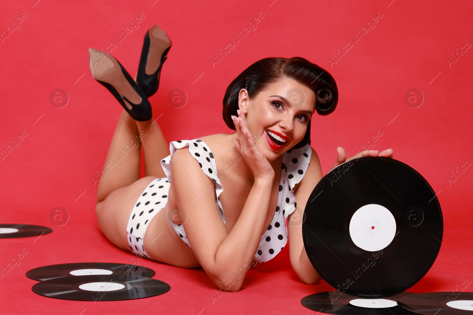 Photo of Pin-up woman in bikini with vinyl records on red background