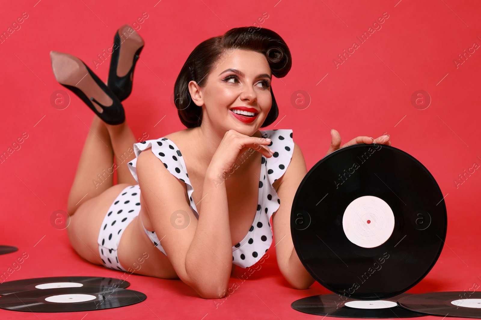 Photo of Pin-up woman in bikini with vinyl records on red background