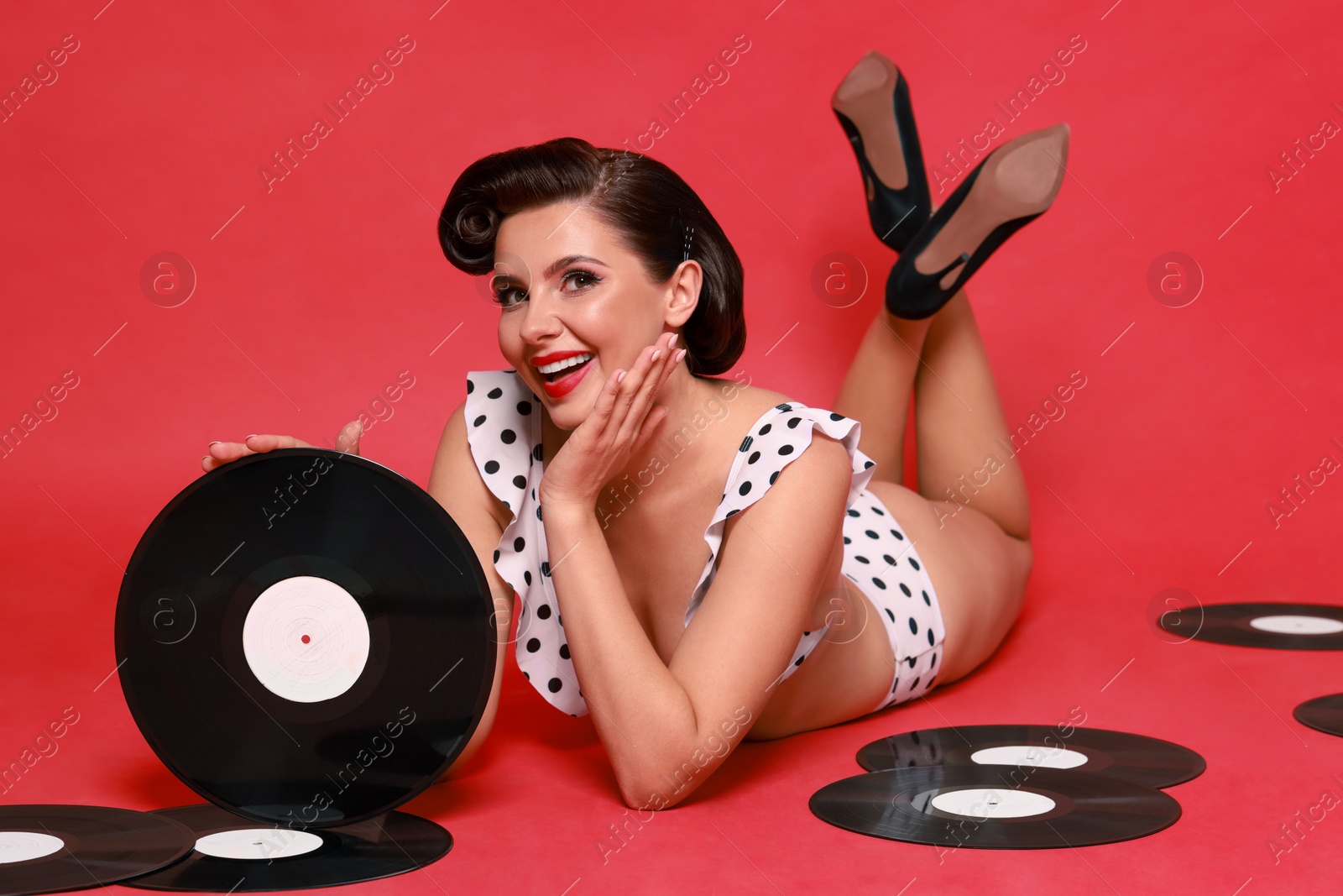 Photo of Pin-up woman in bikini with vinyl records on red background