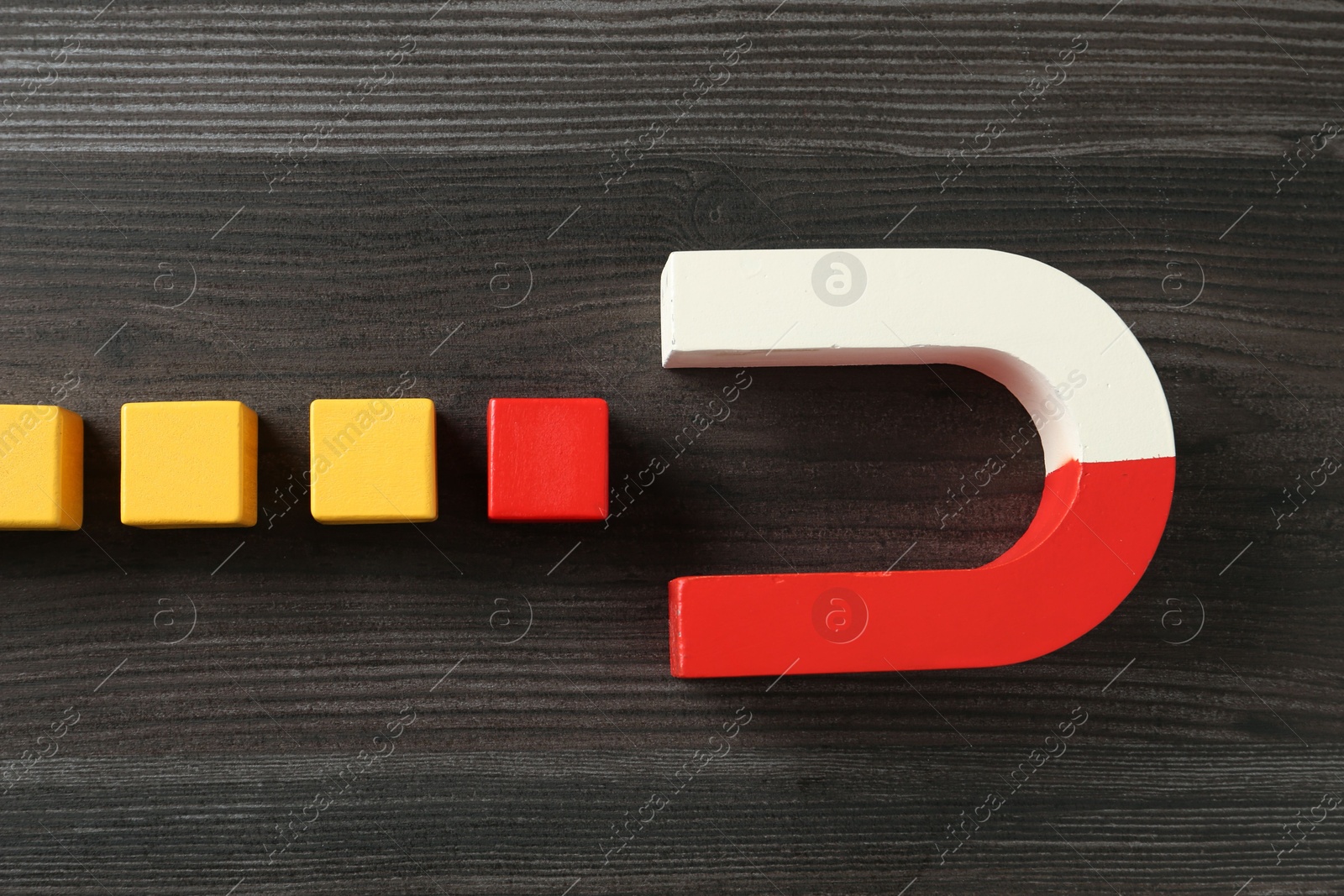 Photo of Magnet attracting with colorful cubes on wooden table, flat lay