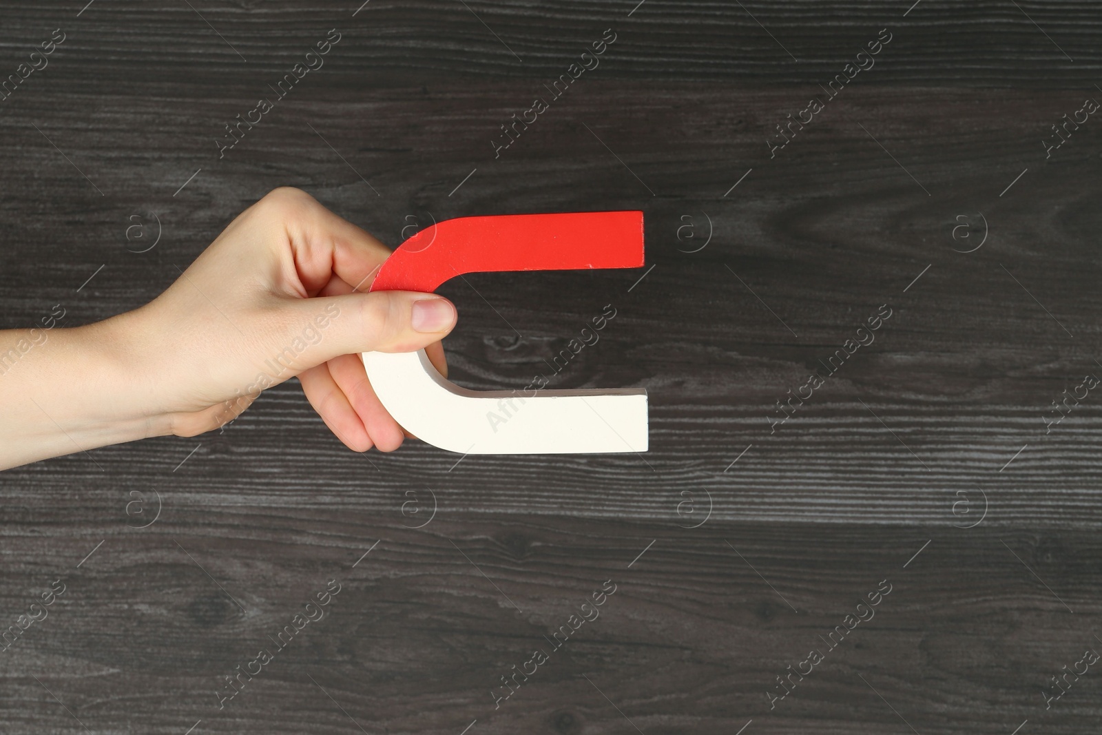 Photo of Woman with horseshoe magnet on wooden background, closeup