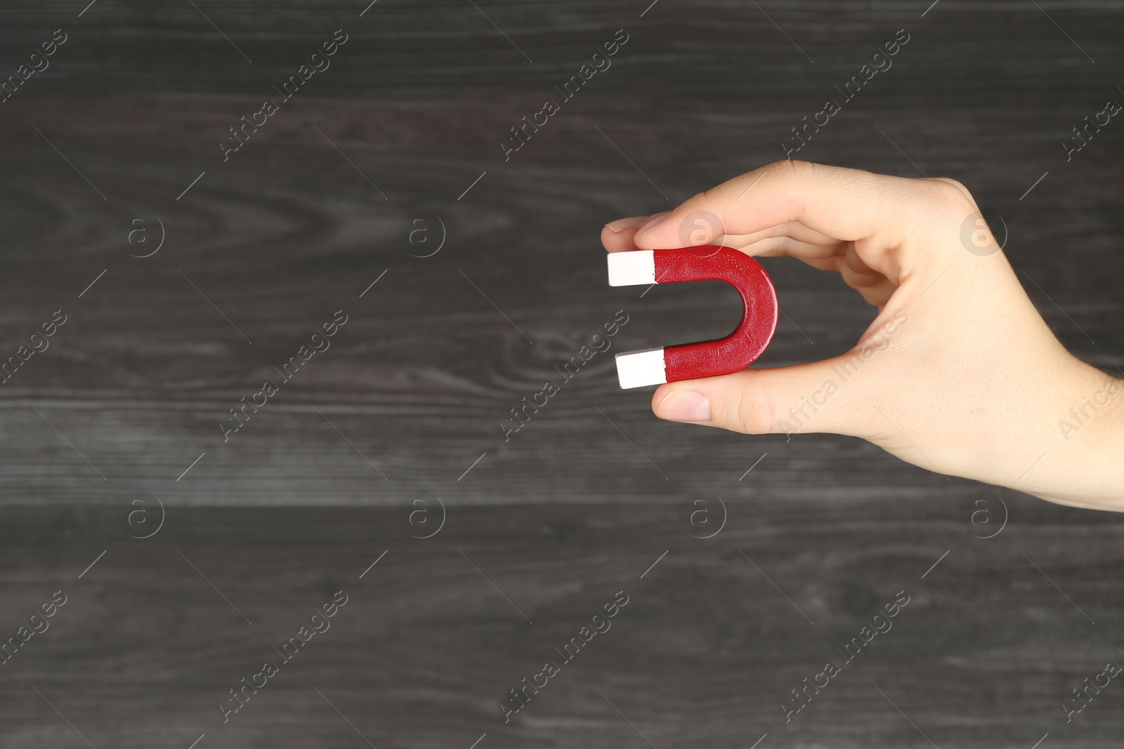 Photo of Woman with horseshoe magnet on wooden background, closeup. Space for text