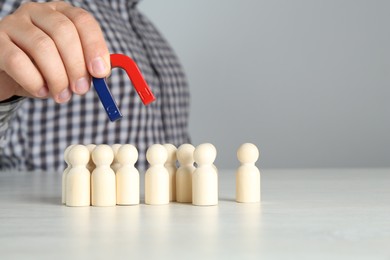 Photo of Man with magnet attracting wooden human figures at light table, closeup