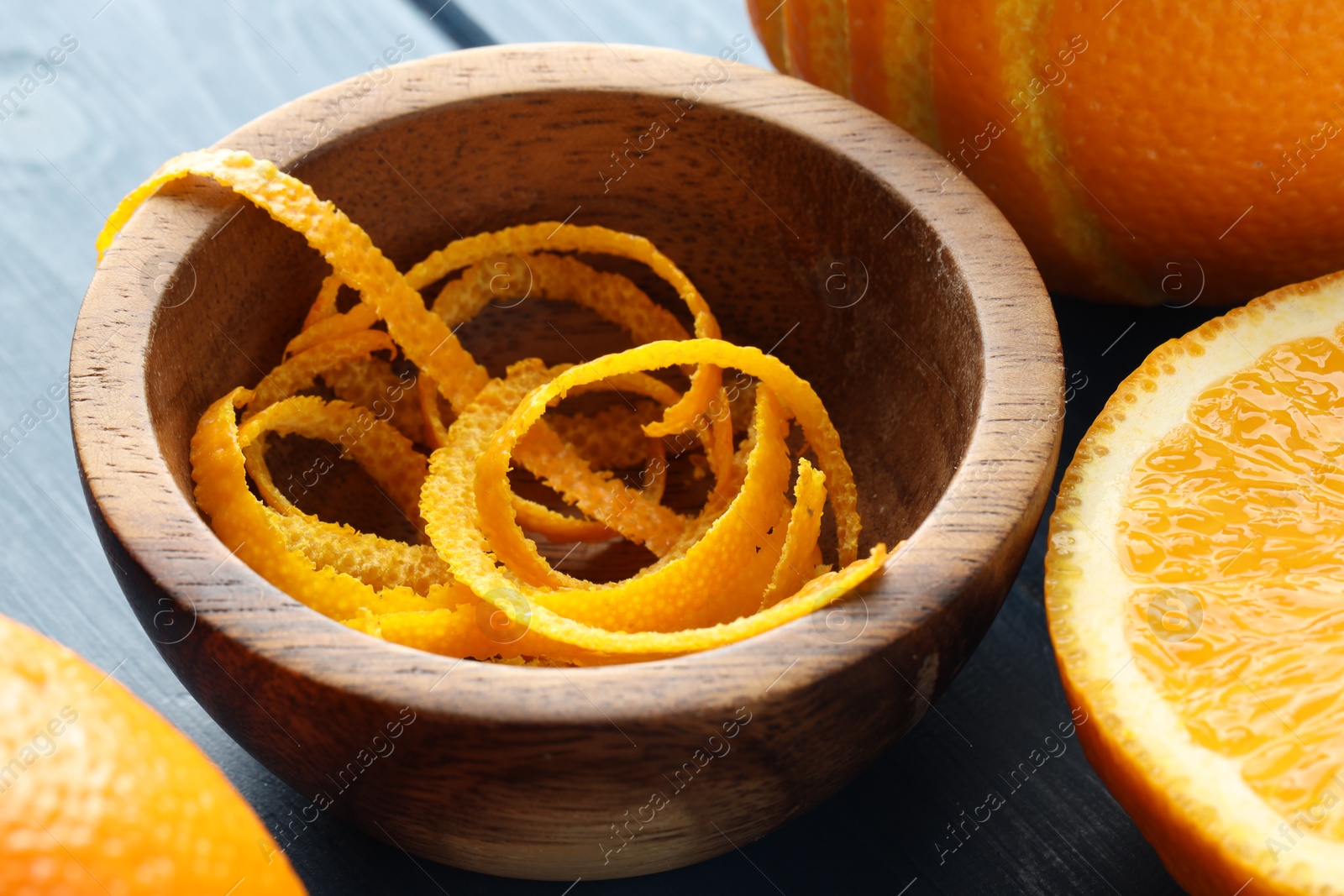 Photo of Bowl with fresh orange zest and fruits on blue wooden table, closeup