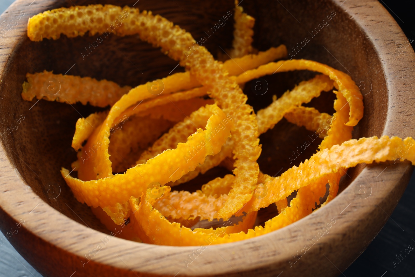 Photo of Fresh orange zest in wooden bowl, closeup