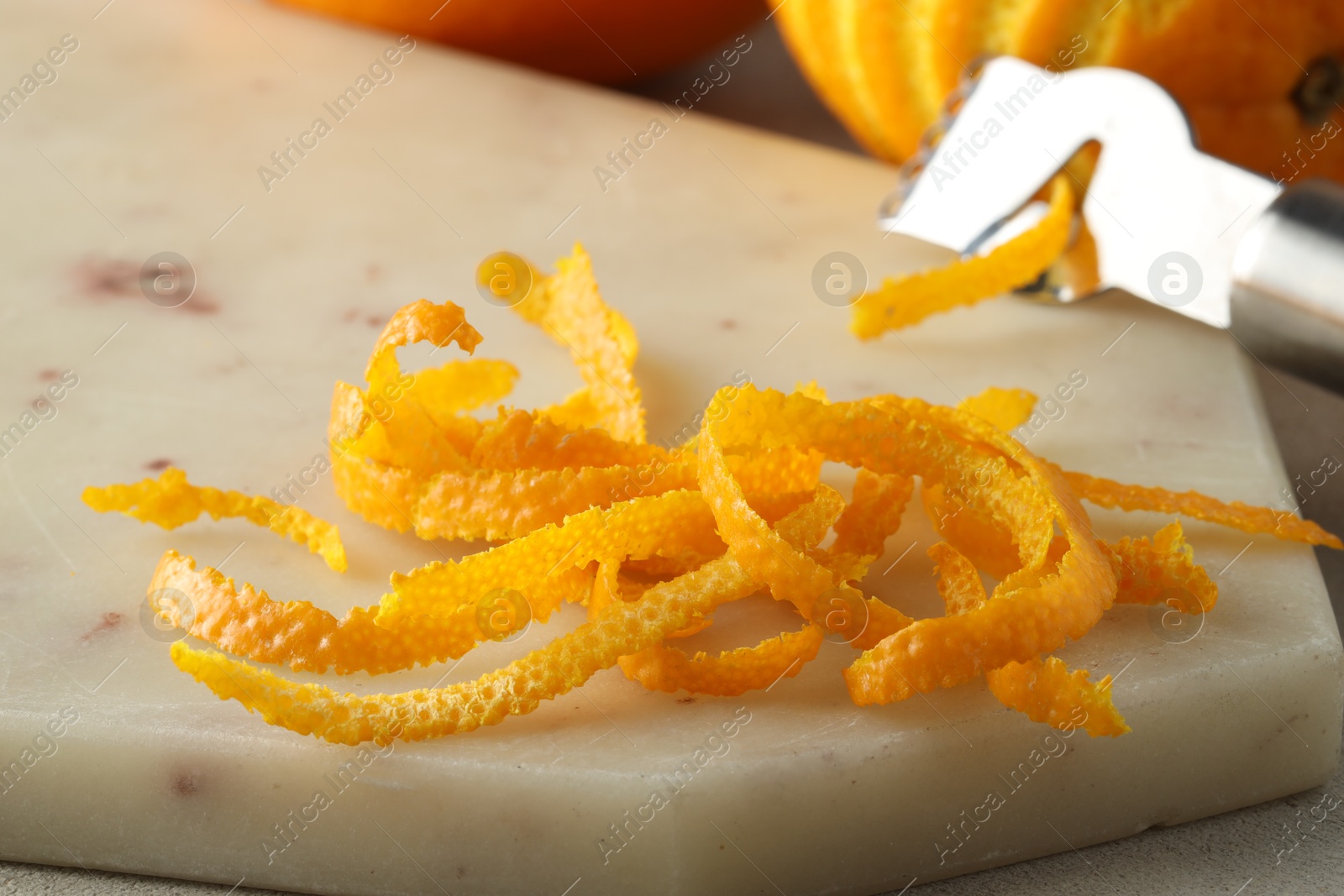 Photo of Fresh orange zest on light textured table, closeup