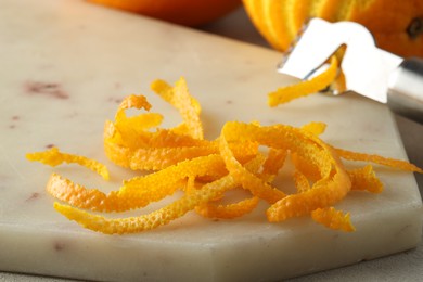 Fresh orange zest on light textured table, closeup