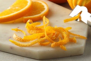 Photo of Fresh orange zest and slices of fruit on light textured table, closeup