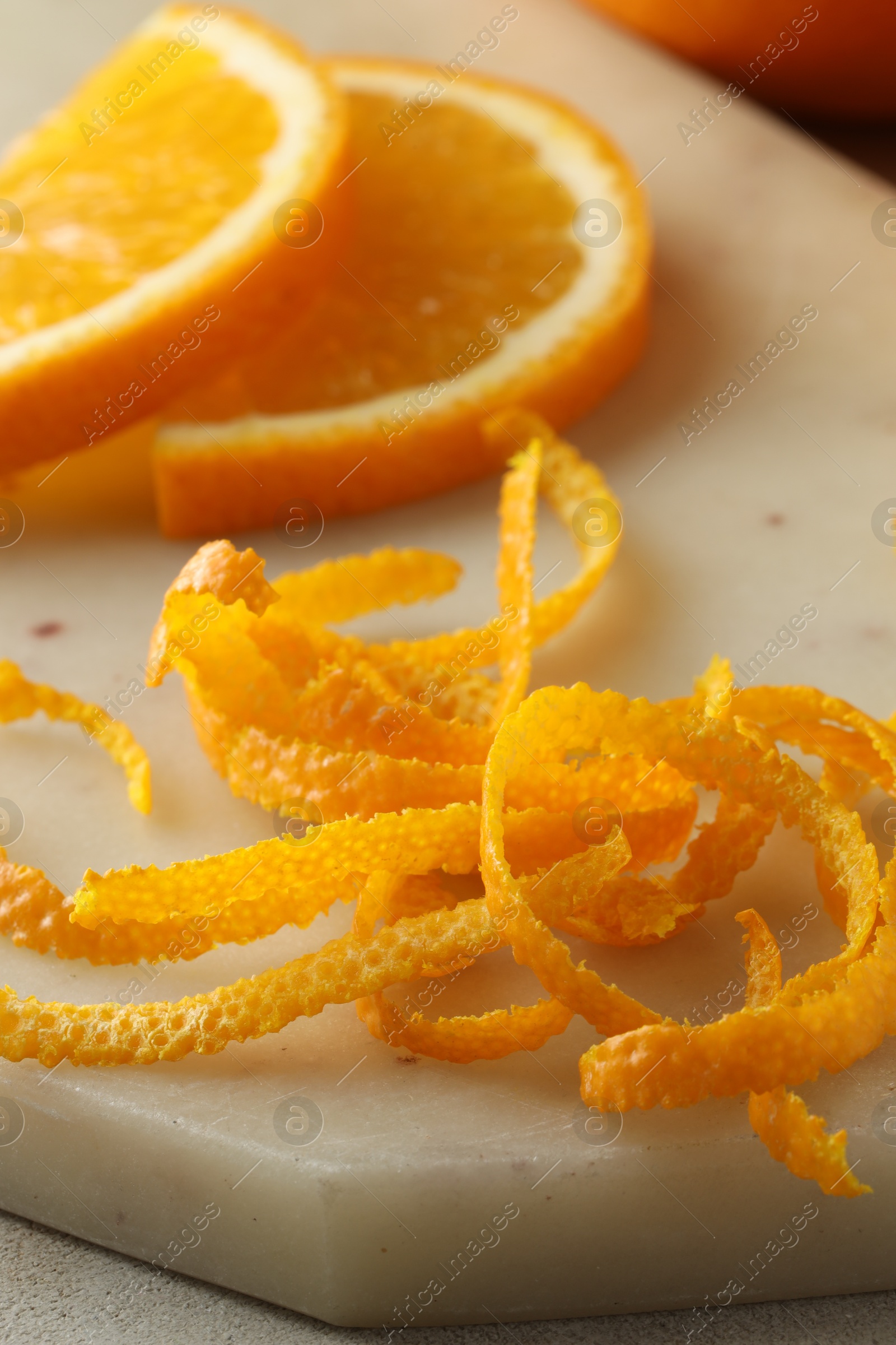 Photo of Fresh orange zest and slices of fruit on light textured table, closeup