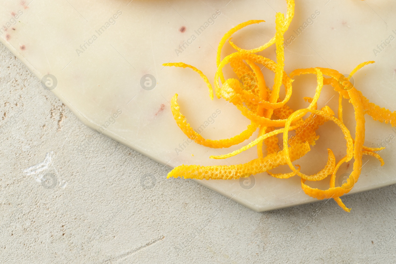 Photo of Fresh orange zest on light textured table, top view. Space for text