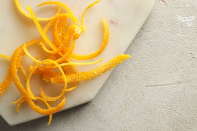 Photo of Fresh orange zest on light textured table, top view. Space for text