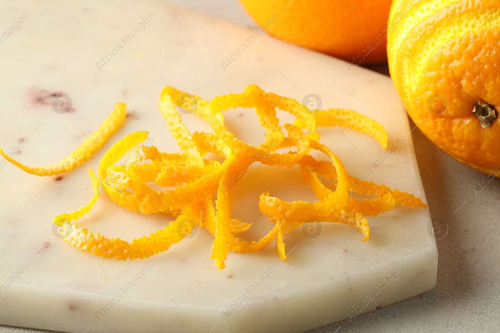 Photo of Fresh orange zest and fruits on light textured table, closeup