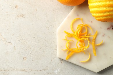 Photo of Fresh orange zest and fruits on light textured table, flat lay. Space for text