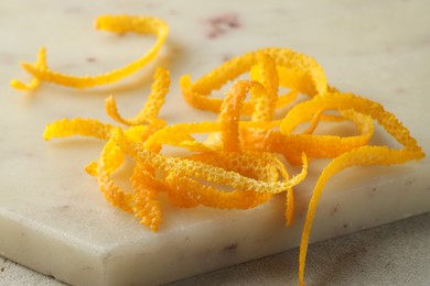 Photo of Fresh orange zest on light textured table, closeup