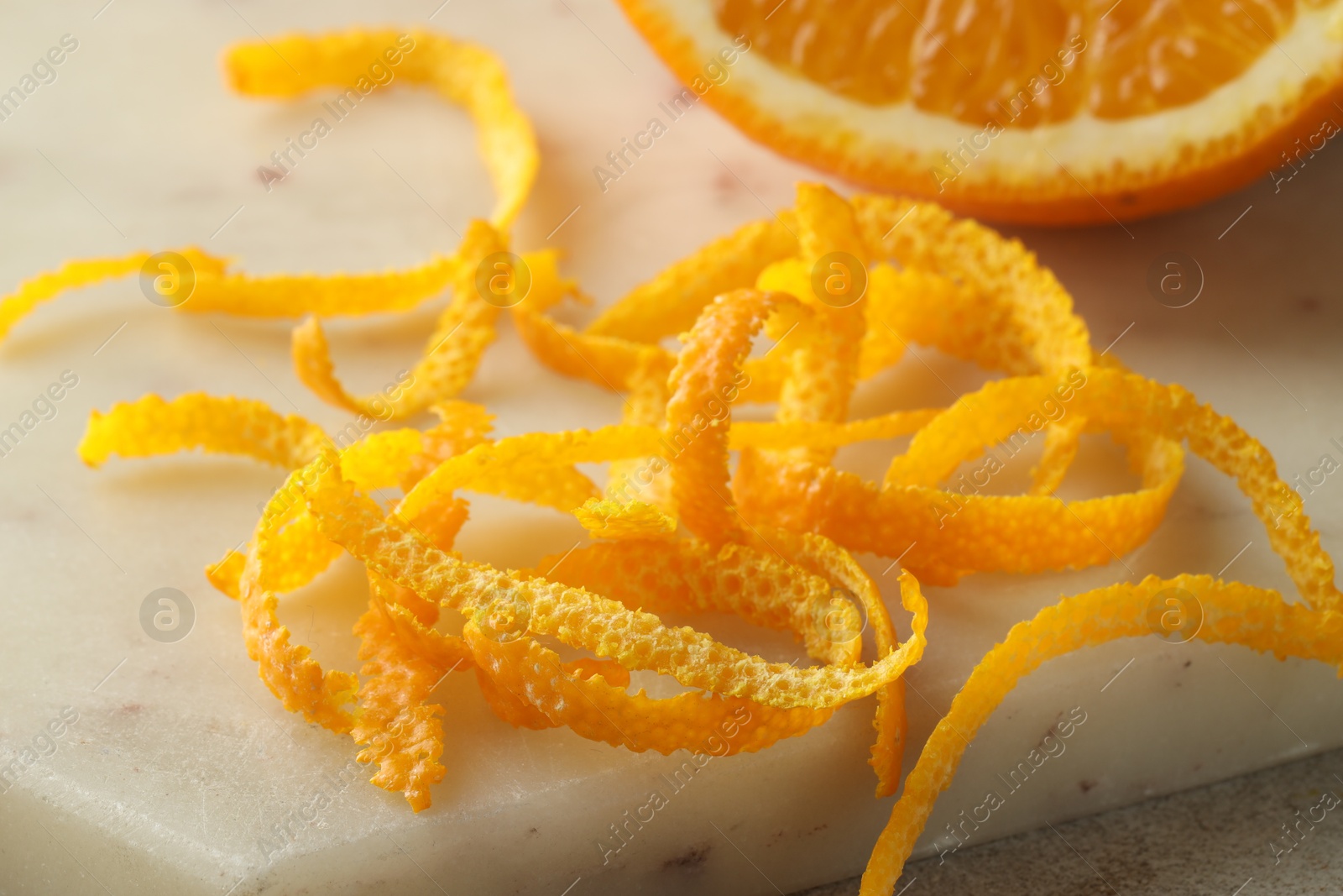 Photo of Fresh orange zest and fruit on light textured table, closeup