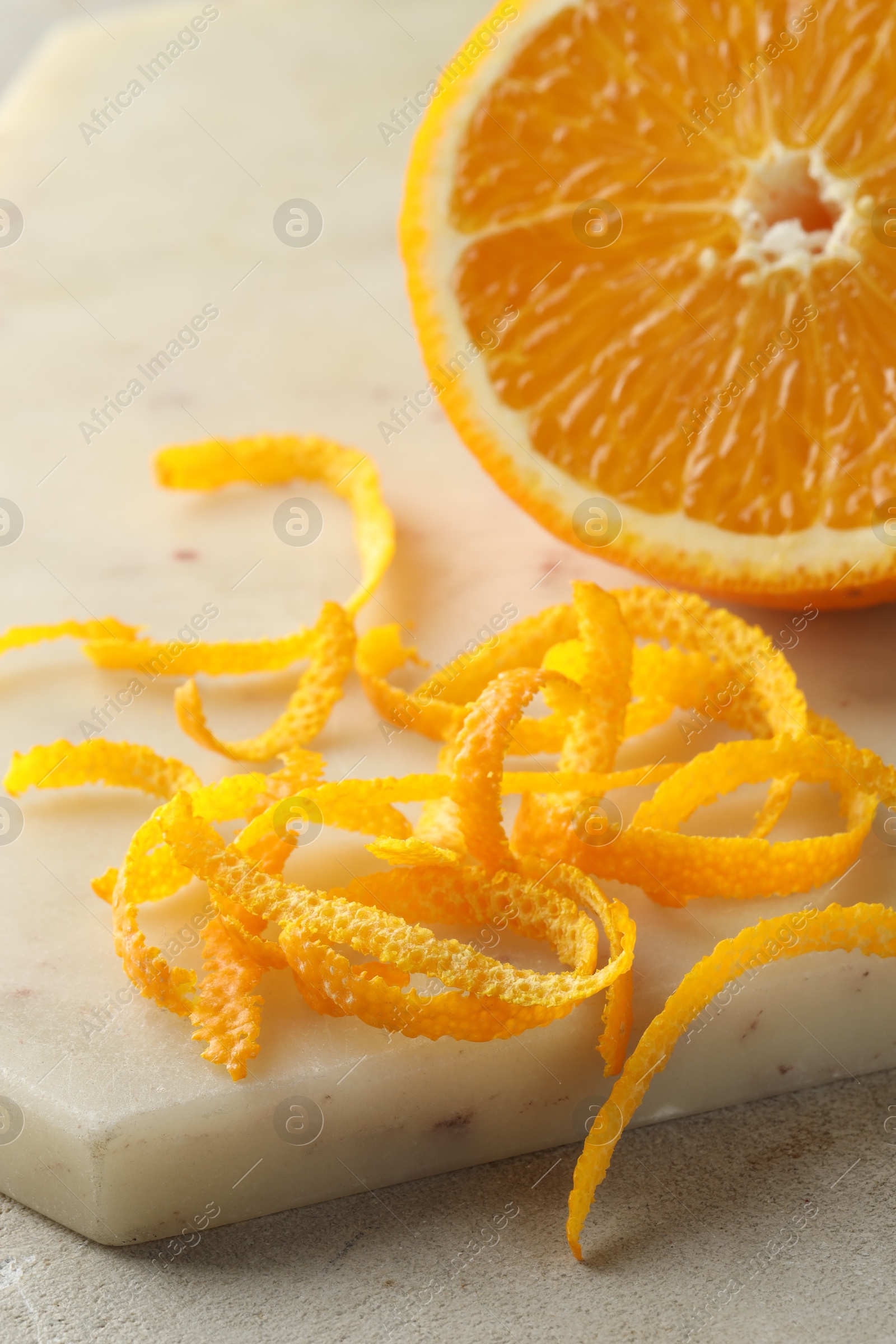 Photo of Fresh orange zest and fruit on light textured table, closeup