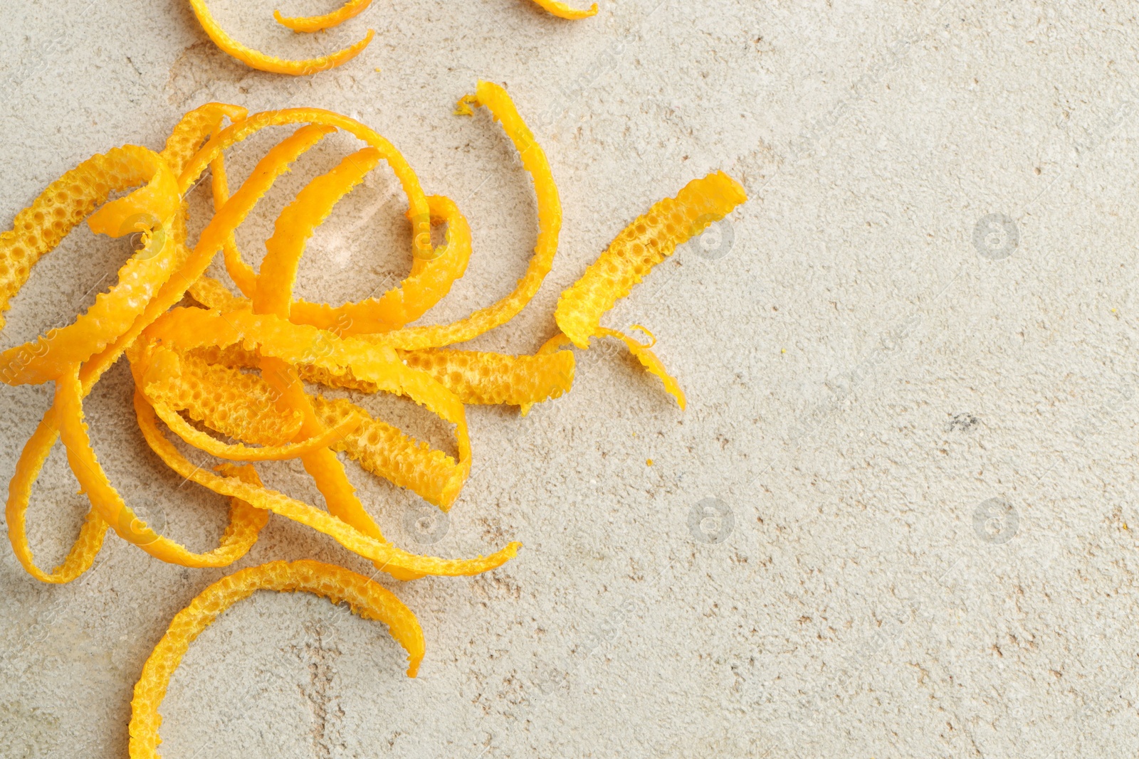 Photo of Fresh orange zest on light textured table, top view. Space for text