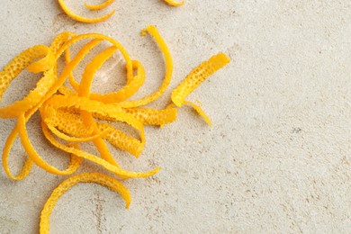 Photo of Fresh orange zest on light textured table, top view. Space for text