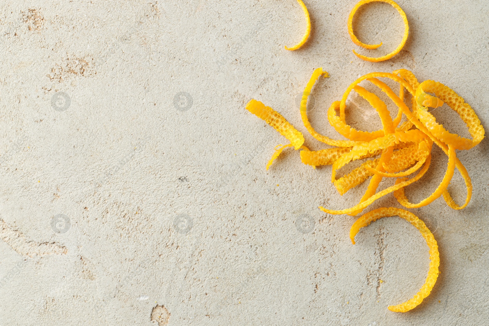 Photo of Fresh orange zest on light textured table, top view. Space for text