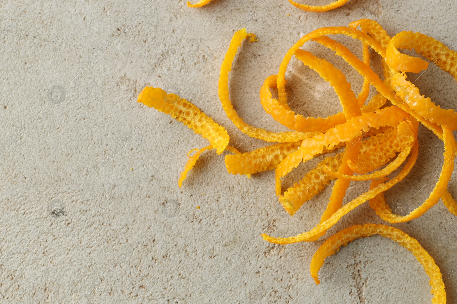 Photo of Fresh orange zest on light textured table, top view. Space for text