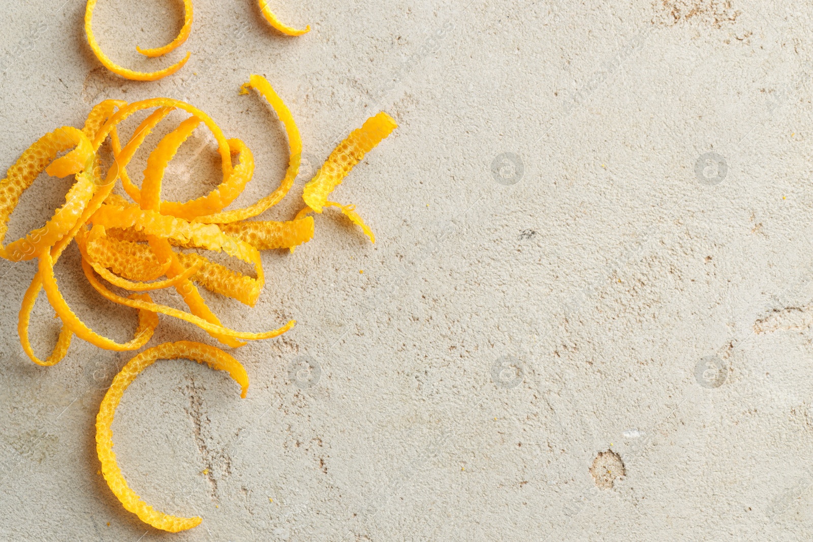 Photo of Fresh orange zest on light textured table, top view. Space for text