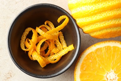 Photo of Fresh orange zest and fruits on light textured table, flat lay