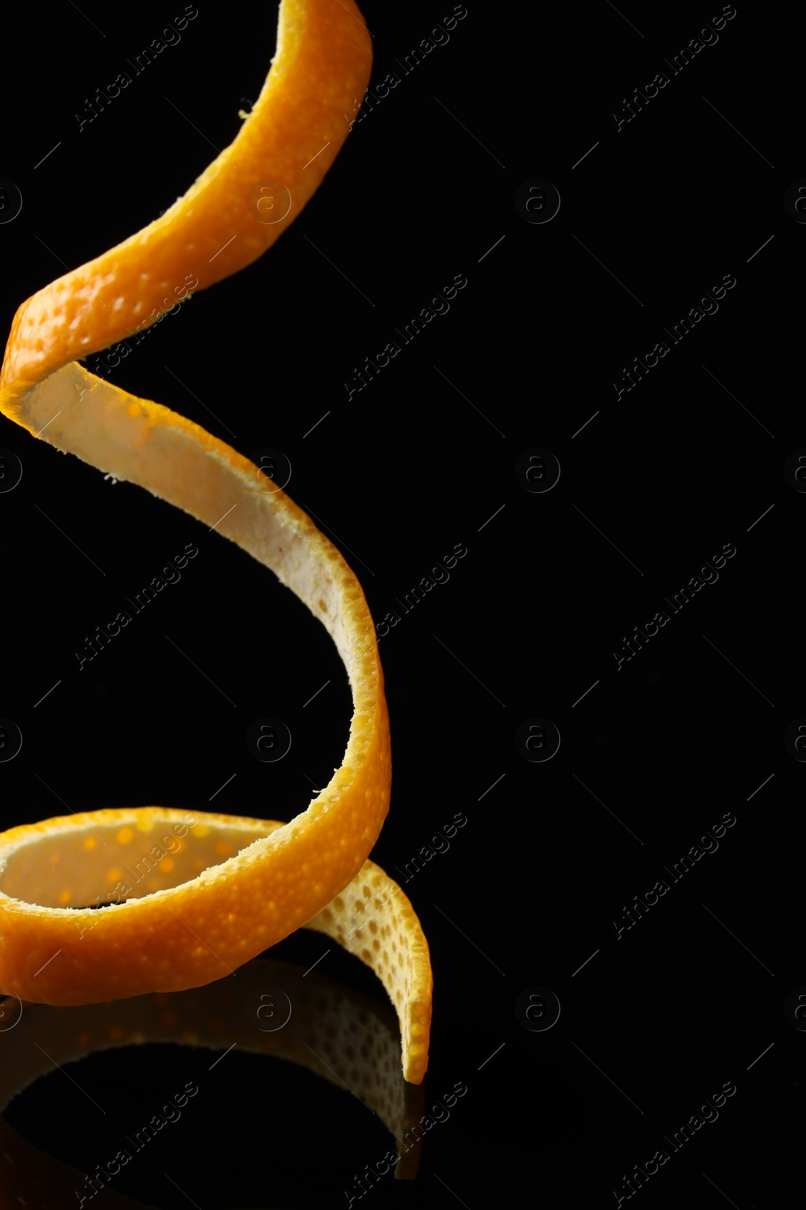 Photo of One fresh orange peel on black mirror surface, closeup. Space for text