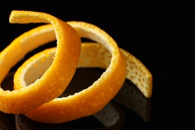 Photo of One fresh orange peel on black mirror surface, closeup