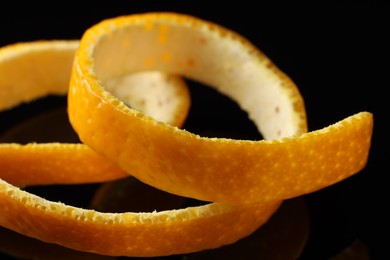 Photo of One fresh orange peel on black background, closeup