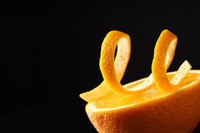 Photo of Fresh orange peel and half of fruit on black background, closeup. Space for text